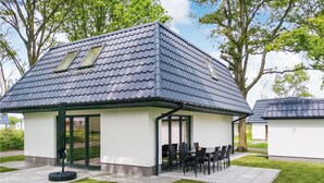 Et moderne hus med tegltag, en overdækket terrasse med udemøbler og en velplejet græsplæne.