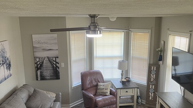 A living room with a sofa, a recliner, a coffee table, a TV stand, and a ceiling fan. - Hummingbird Haven-3 Bed 2 Bath River House (Clifton)