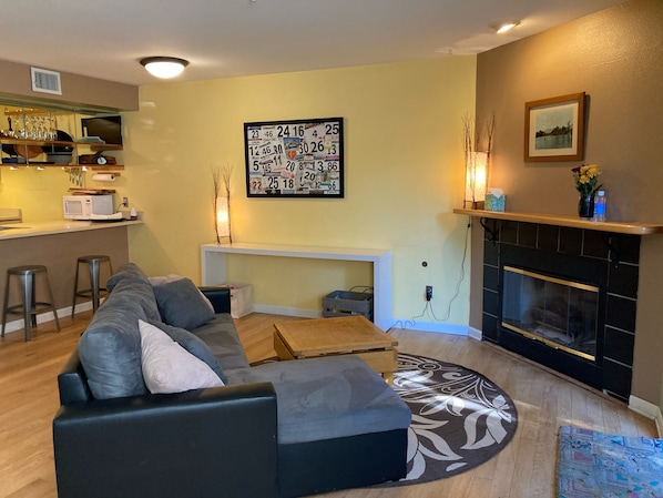 A living room with a sofa, a fireplace, a kitchen area, and a wall calendar. - Central Boulder Studio Condo - Quiet Space Close to Downtown! (Boulder)