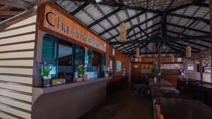 Un restaurant à l’intérieur en bois, un comptoir sur lequel est affiché un panneau indiquant « Charleena Beach Resort », et un tableau affichant le menu, intitulé « The Bay ».
