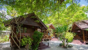 Une cabane en bois dotée d’un porche et d’un escalier menant à l’entrée, entourée d’arbres et de plantes.