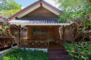 A wooden house with a porch, a dining area with chairs, and a small garden.