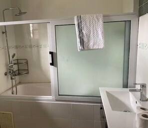 Een douche, handdoeken, zeep, toiletpapier