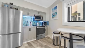 A modern kitchen with stainless steel appliances, a tiled backsplash, and a window overlooking a building.