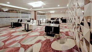 A conference room with multiple tables and chairs, a patterned carpet, and a modern ceiling design. -  Zip By Spree Hotels Surat (Surat)