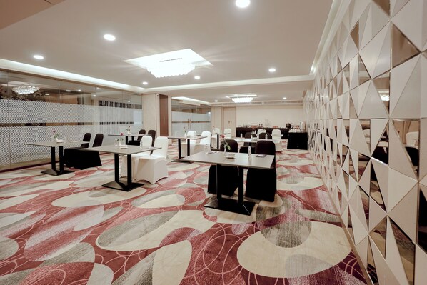 A conference room with multiple tables and chairs, a patterned carpet, and a modern ceiling design. -  Zip By Spree Hotels Surat (Surat)