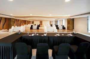 A conference room with a long table, black and white chairs, and a stage area.