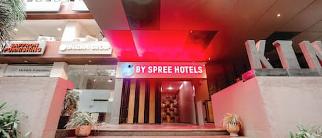A hotel entrance with a red-lit sign for By Spree Hotels, a sign for Saffron Furnishing, and a large 'K' structure.