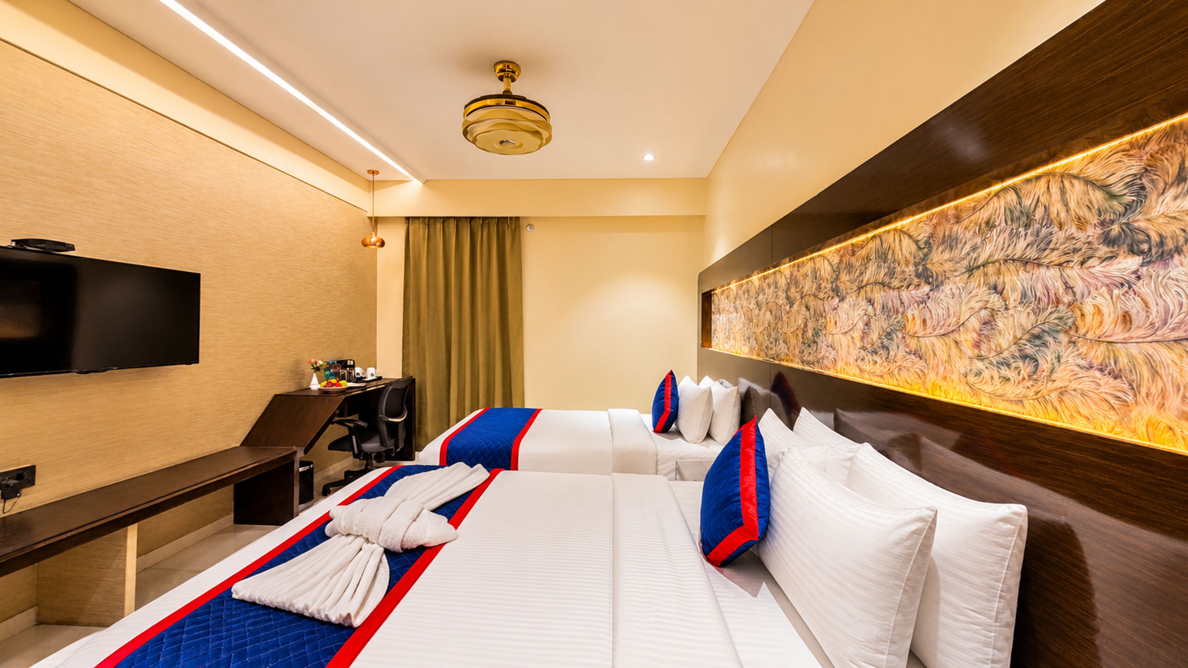 A hotel room with a large bed, a desk, a flat-screen TV, and a decorative wall mural.