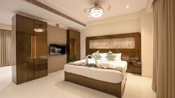 A modern hotel room with a large bed, a flat-screen TV, a wardrobe, and a ceiling light. -  Zip By Spree Hotels Surat (Surat)