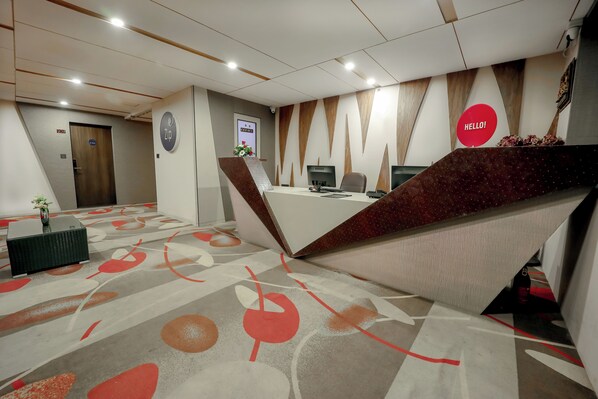 Zona d'entrada d'un hotel modern amb taulell, ordinadors i un cartell que diu 'Hello!'.