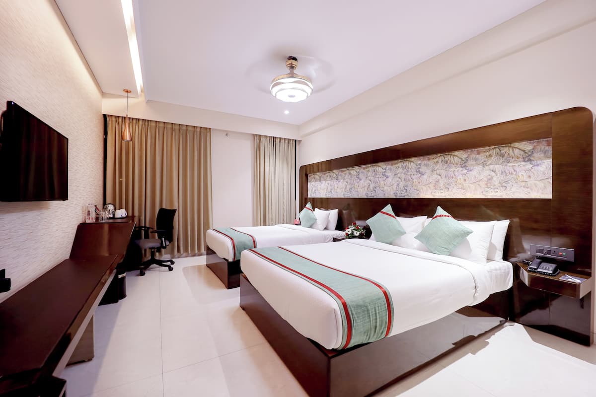 Quarto de hotel com duas camas, uma mesa de escritório, uma cadeira, uma televisão e um criado-mudo com telefone.