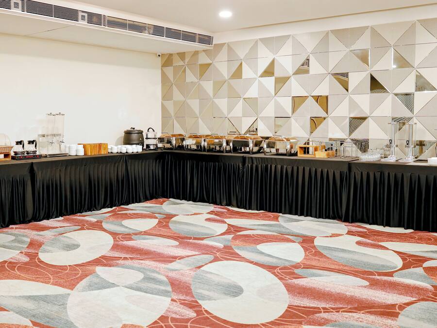 Un salón de conferencias con una larga mesa, una alfombra estampada y un diseño geométrico en la pared.