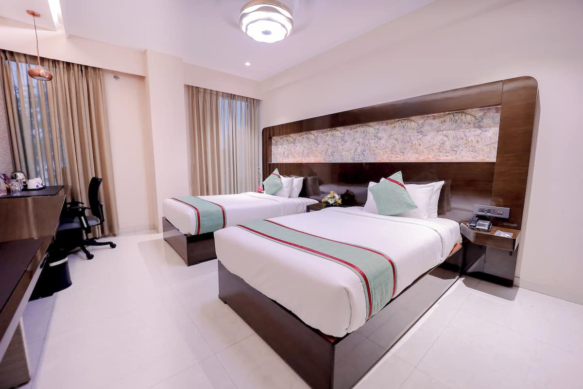 Quarto de hotel com duas camas, uma escrivaninha e uma cadeira.