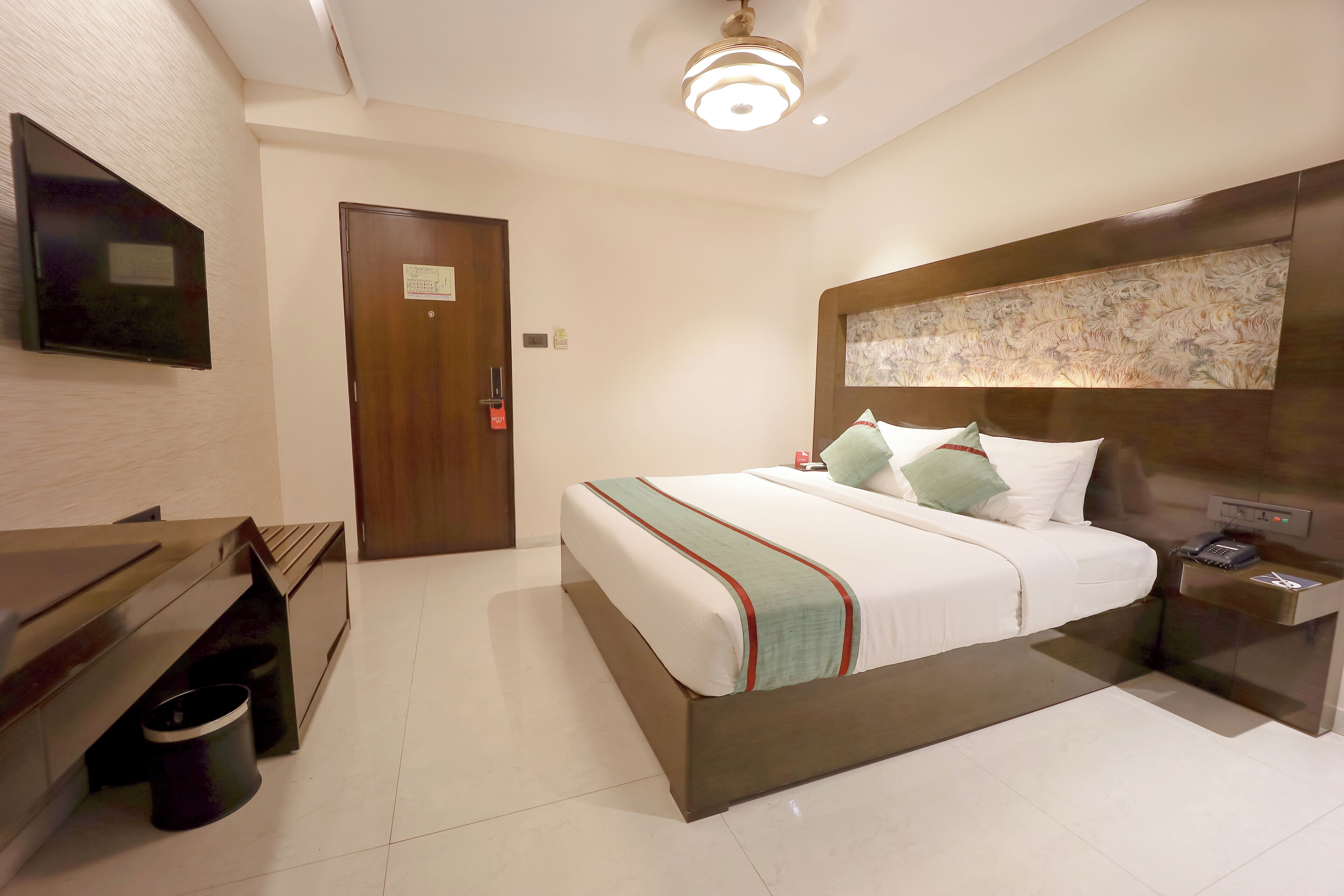 A hotel room with a bed, bedside table, and a television mounted on the wall.