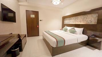 A hotel room with a bed, bedside table, and a television mounted on the wall.