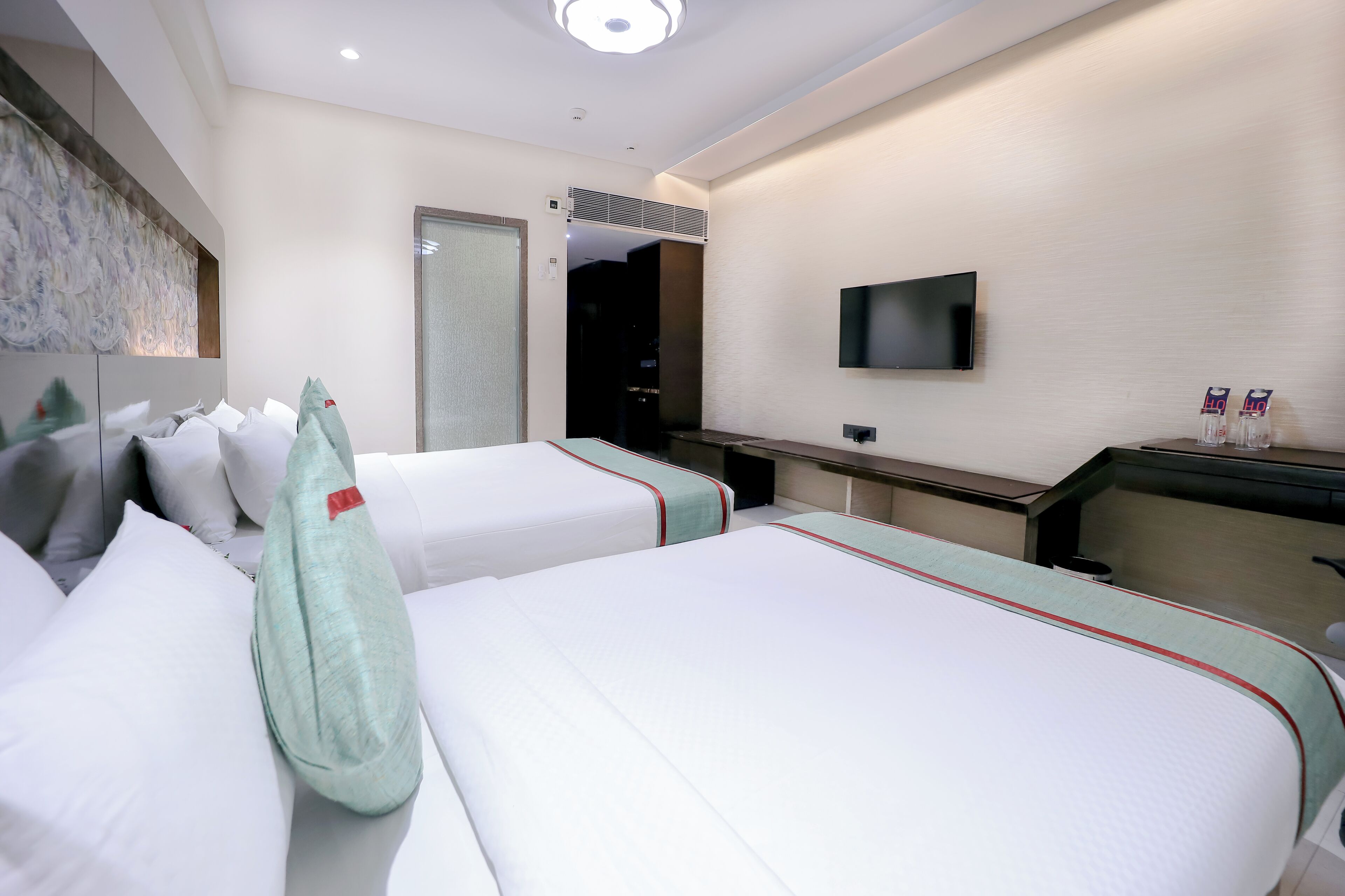 Une chambre d’hôtel avec deux lits, un bureau, un téléviseur à écran plat et un miroir.