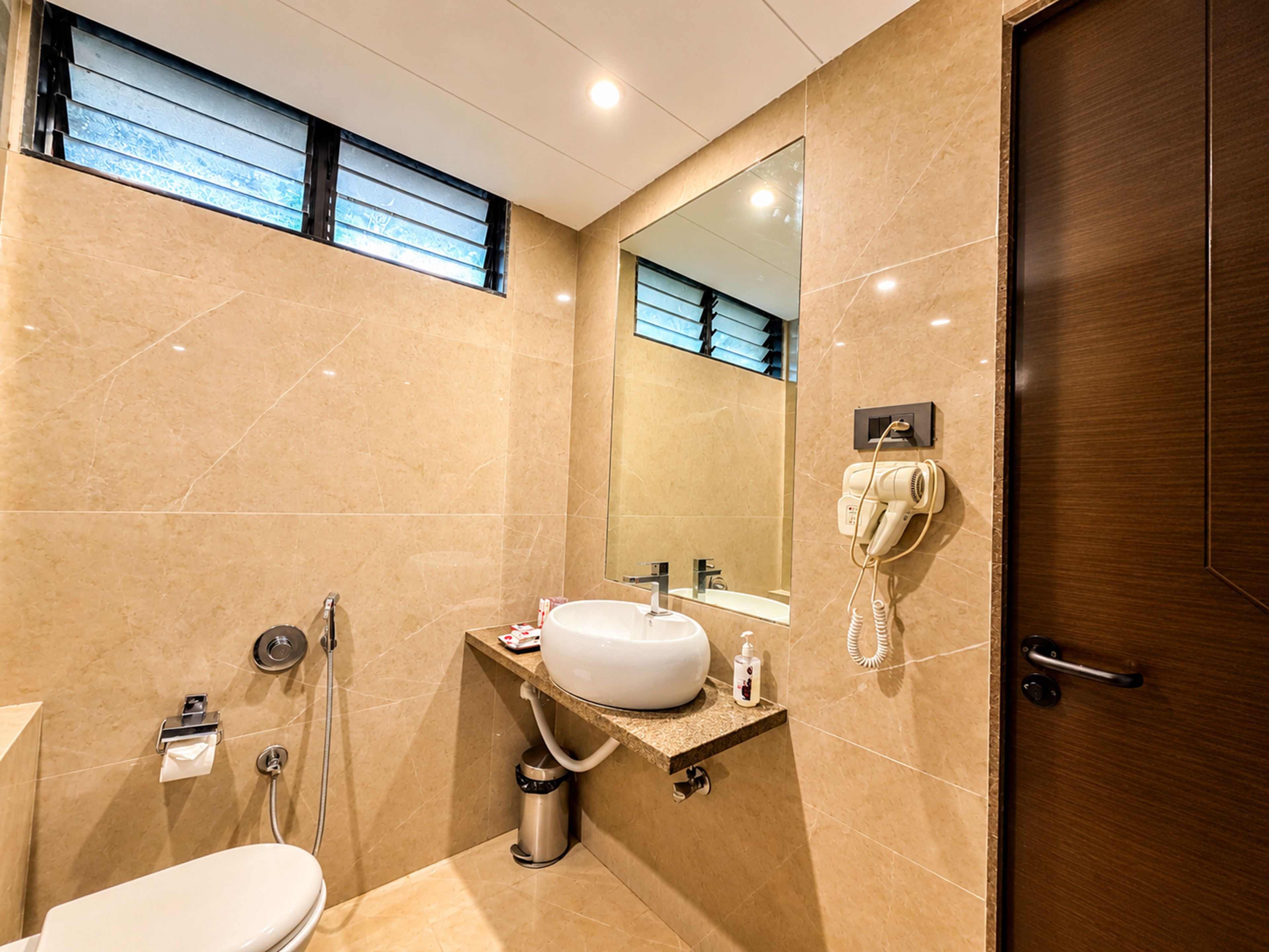 Une salle de bain moderne équipée de toilettes, d’un lavabo, d’un miroir et d’un sèche-cheveux.