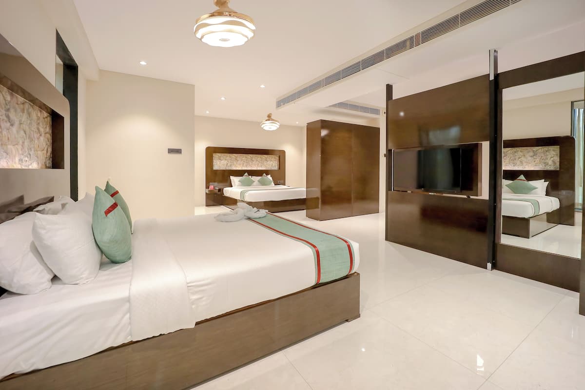 Quarto de hotel moderno com uma cama grande, uma toucador com espelho e uma televisão.
