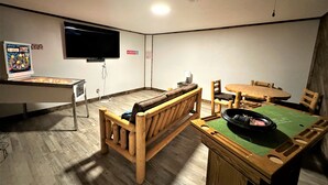 A room with a wooden bench, a table with chairs, a television mounted on the wall, and a poster on the wall. - The Hideaway Oliver Springs, Only Min from Windrock Park (Oliver Springs)