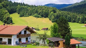 Ein Haus mit rotem Dach, einem Balkon und einer kleinen Holzhütte am See.