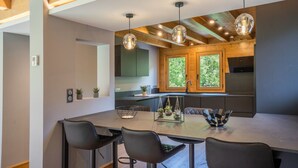 A modern kitchen with wooden beams, pendant lights, and a large island with seating.