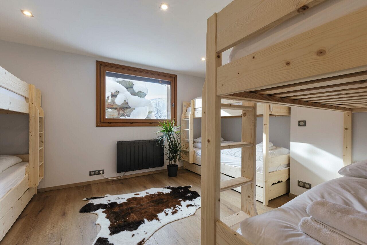 A modern, compact room with bunk beds, a radiator, a window with a snowy view, and a cowhide rug.