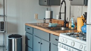 Eine moderne Küche mit grauen Schränken, einer Holz Arbeitsplatte, einer Edelstahl-Spüle und einem weißen Herd.