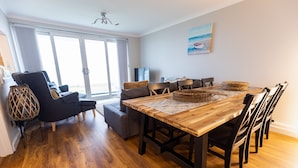Un salon moderne avec une table à manger en bois, des chaises noires et un canapé gris.
