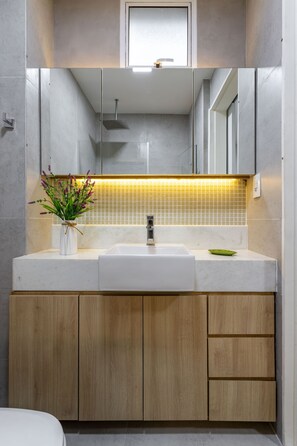 A modern bathroom with a white sink, wooden cabinets, and a mirror above the sink. - Apartment in Copacabana Suite Bi204 (Rio de Janeiro)