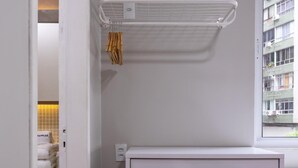 A modern bedroom with a built-in wardrobe, a window with a view of buildings, and a wall-mounted air conditioner. - Apartment in Copacabana Suite Bi204 (Rio de Janeiro)