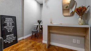 A hotel room with a herringbone wood floor, a white console table, a mirror, a vase with dried flowers, and a framed sign on the wall. - Apartment in Copacabana Suite Bi204 (Rio de Janeiro)