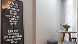 A modern hotel room with a herringbone wood floor, a large mirror, a small table with a plant, and a wall-mounted sign listing nearby attractions. - Apartment in Copacabana Suite Bi204 (Rio de Janeiro)