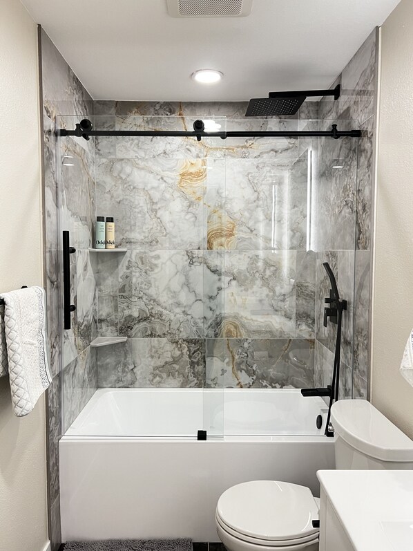 Une salle de bain moderne avec une douche à parois de verre, une baignoire blanche et des toilettes.
