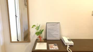 A reception desk with a framed service menu, a plant, a telephone, and a mirror.