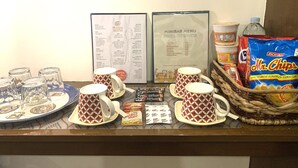 A counter with coffee mugs, a menu, snacks, and a snack basket. - Davao Airport View Hotel (Davao)