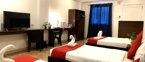A hotel room with two beds, a desk with a TV, a chair, and a wardrobe.