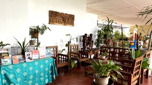 A room with wooden furniture, potted plants, and informational posters on a table. - Davao Airport View Hotel (Davao)