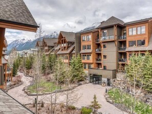 A lodge with multiple wooden buildings, a central courtyard, and a mountain backdrop. - Rest & Recharge | Your Mountain Resort Escape (Canmore)