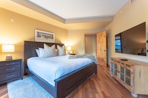 Une chambre à coucher avec un grand lit, une tête de lit en bois, des lampes de chevet, une commode et un grand miroir.