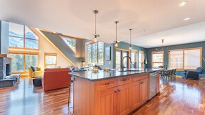 A spacious kitchen with a large island, wooden cabinets, and pendant lighting. - Scenic Bliss Penthouse | Prime Location (Canmore)