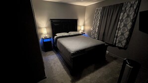 A bedroom with a bed, two bedside tables with lamps, a ceiling light, and a window with curtains. - Large home 2 living rooms, 4 bedrooms. Near lakes and great hunting and fishing. (Agra)