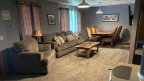 A living room with a sofa, a coffee table, and a dining table with chairs. - Large home 2 living rooms, 4 bedrooms. Near lakes and great hunting and fishing. (Agra)