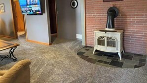 A room with a fireplace, a television mounted on the wall, and a carpeted floor. - Large home 2 living rooms, 4 bedrooms. Near lakes and great hunting and fishing. (Agra)