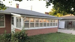 A single-story brick house with a large windowed front porch. - Large home 2 living rooms, 4 bedrooms. Near lakes and great hunting and fishing. (Agra)