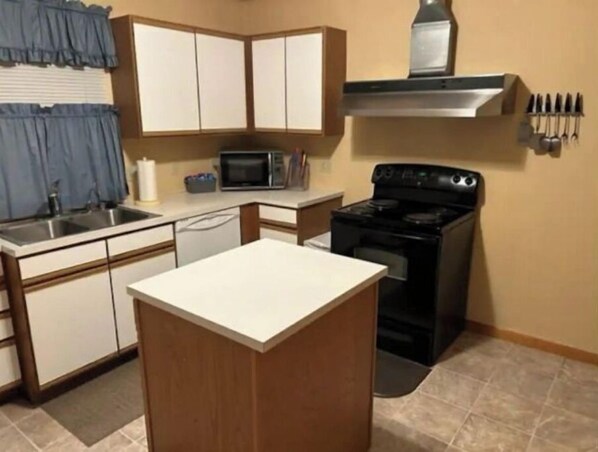 A compact kitchen with a stove, microwave, and sink. - Large home 2 living rooms, 4 bedrooms. Near lakes and great hunting and fishing. (Agra)
