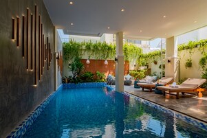 Un área de piscina interior moderna con una piscina cristalina, sillas de descanso y paredes verticales cubiertas de jardines.
