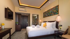 Une chambre d’hôtel avec un grand lit, un bureau, une chaise, un téléviseur fixé au mur et un tableau au-dessus du lit.