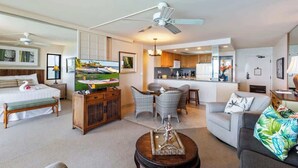 A hotel room with a bed, a TV, a dining area, and a kitchenette.