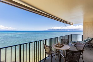 Enjoy the ocean view from this balcony with wicker chairs and a small table.